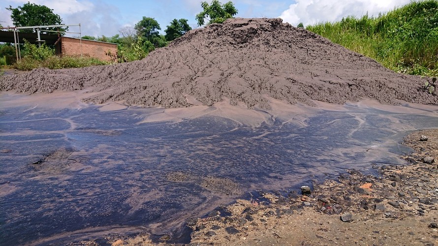 Sau cơn mưa, lượng nước màu đen từ chất thải đổ lênh láng trên nền đất