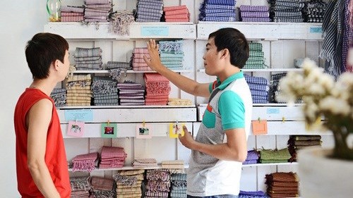 Nguyễn Hữu Nghĩa (bên phải) tư vấn cho khách hàng chọn mua khăn rằn