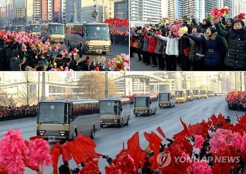 Người dân Triều Tiên vẫy cờ, hoa khi đoàn xe chở các nhà khoa học hạt nhân nước này đi qua. Ảnh: Yonhap