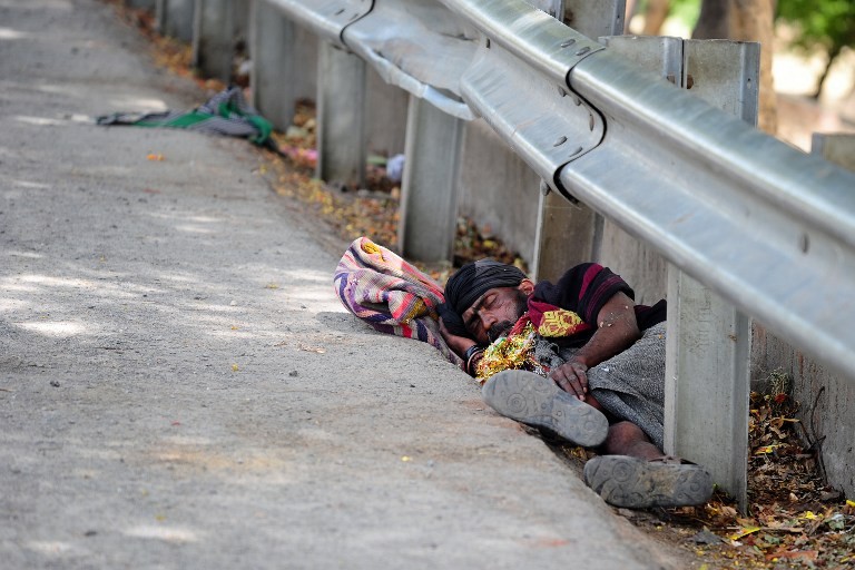 Một người đàn ông mệt lả nằm ven đường bởi nắng nóng.