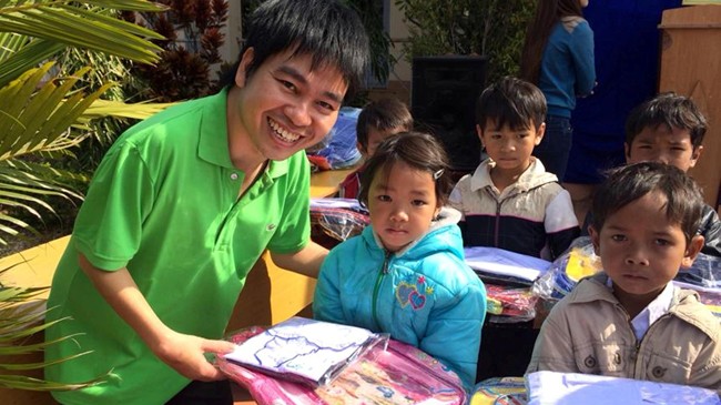 Anh Nguyễn Duy Học trao cặp, áo cho trẻ em trong chương trình “Vì trẻ em nghèo”. Ảnh: L.H.