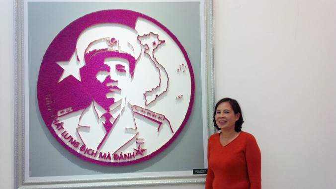 Bà Thục bên bức tranh ghép bằng diêm chân dung Đại tướng Nguyễn Chí Thanh. Ảnh: Trung Dũng.