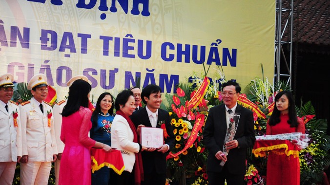 GS trẻ nhất Phan Thanh Sơn Nam nhận chứng nhận chức danh và hoa do Phó Chủ tịch nước Nguyễn Thị Doan và Bộ trưởng Bộ GD&ĐT Phạm Vũ Luận trao tặng. Ảnh: Hồ Thu.