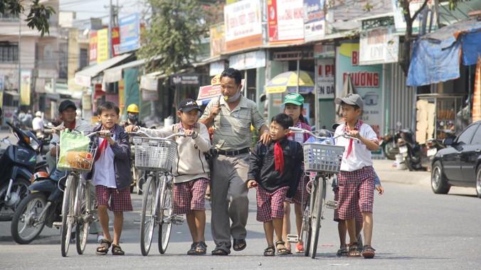 Anh Lê Văn Thịnh dẫn các em học sinh qua đường.