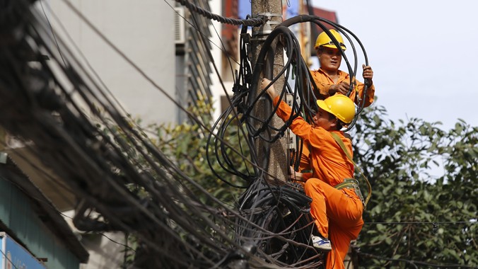 Công nhân Công ty Điện lực đang đấu nối cáp điện trên phố Khâm Thiên - Hà Nội. Ảnh: Ngọc Châu.