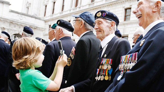 Một cậu bé chụp ảnh các cựu chiến binh ở London.