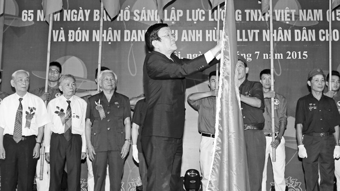 Chủ tịch nước Trương Tấn Sang gắn Danh hiệu Anh hùng Lực lượng vũ trang nhân dân lên lá cờ truyền thống của Đội Thanh niên xung phong 36. Ảnh: TTXVN.