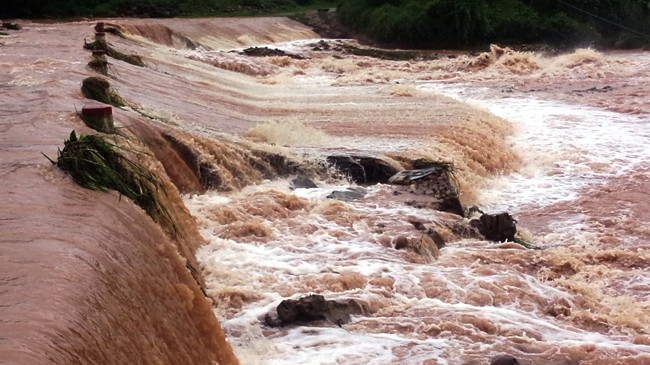 Nước lũ dâng cao cuồn cuộn chảy qua đập Cổ Nhựa trên tỉnh lộ 330 (xã Lương Mông) ngày 2/8. Ảnh: CTV.
