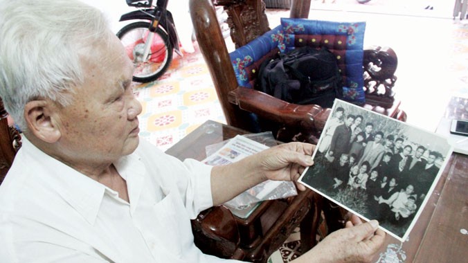 Ông Huyến với tấm ảnh chụp gia tộc liệt sỹ Nguyễn Chưng.