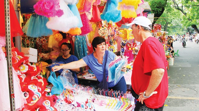 Du khách nước ngoài mua đồ chơi Tết Trung thu tại phố Hàng Mã. Ảnh: Quang Lộc.