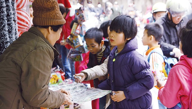 Học sinh tiểu học ở Hà Nội đang mua miếng dán độc hại có xuất xứ Trung Quốc trước cổng trường. Ảnh: Như Ý.