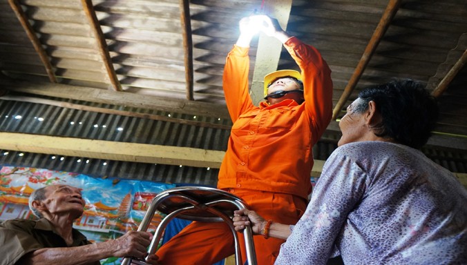Vợ chồng ông Phan Thanh Quang (ấp Mũi, xã Đất Mũi, Ngọc Hiển, Cà Mau) vui mừng được công nhân ngành điện thay thế đường dây, bóng đèn mới.