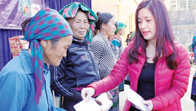 Bí thư Đoàn Ngân hàng BIDV chi nhánh Lào Cai Nguyễn Minh Hương trao quà cho các hộ nghèo ở xã Pha Long (Mường Khương, Lào Cai). Ảnh: Trung Hiền.