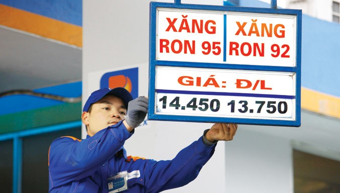 Nhân viên cây xăng trên đường Trần Quang Khải, Hà Nội đang treo biển giảm giá xăng xuống mức thấp nhất trong vòng 7 năm qua. Ảnh chụp lúc 15h chiều ngày 18/2. Ảnh: Như Ý.