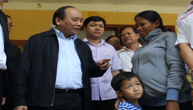 Phó thủ tướng Nguyễn Xuân Phúc trò chuyện cùng chị Hồ Thị Hiếu và cháu Hồ Quốc Khánh.