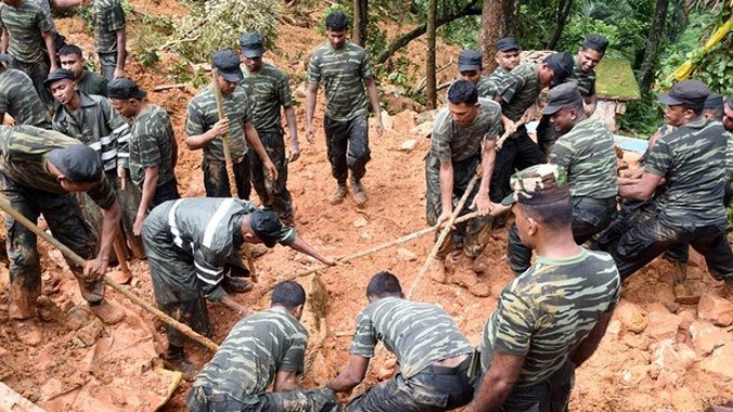 Binh lính Sri Lanka dùng xẻng đào bùn đất để tìm các nạn nhân. Ảnh: Guardian.
