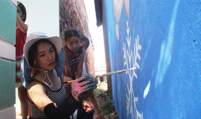 Họa sĩ Oh Ye Seul đang hoàn tác bức tranh người tuyết trên tường nhà dân Tam Thanh. Ảnh: H.Văn.