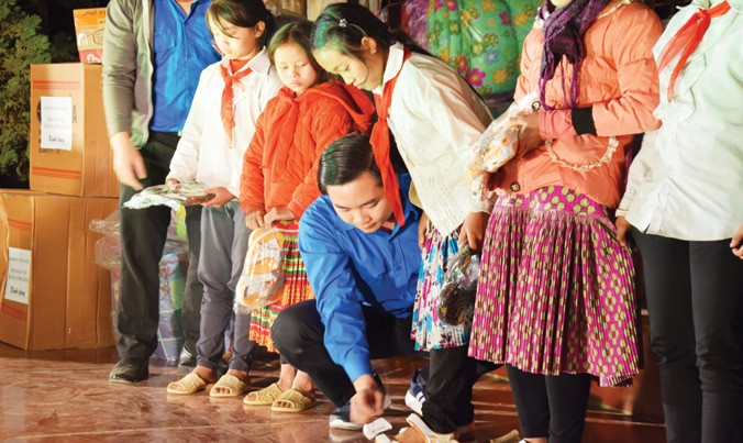 Các tình nguyện viên tặng dép cho các em học sinh nghèo vùng cao tại bản Huổi Phô, huyện Sốp Cộp, Sơn La.