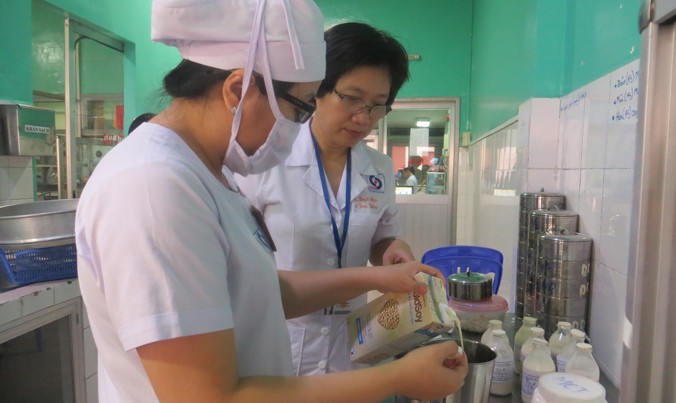 PGS.TS.BS Tạ Thị Tuyết Mai (phải) kiểm tra kỹ từng chai sữa trước khi dùng cho bệnh nhân.