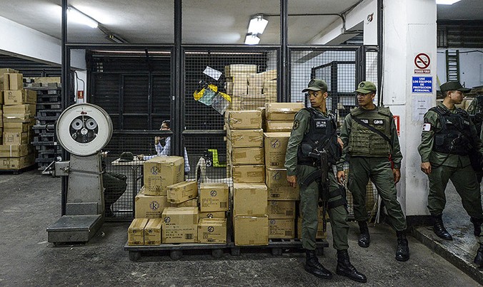 Vệ binh quốc gia Venezuela đứng gác cạnh các hộp chứa đồ chơi tịch thu tại một nhà kho ở thủ đô Caracas. Ảnh: Federico Parra.