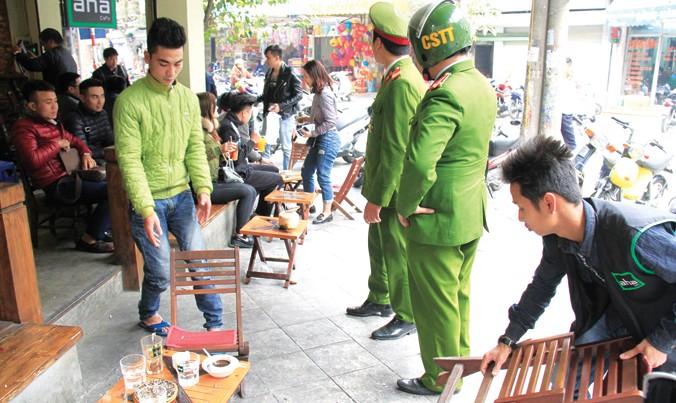 Lực lượng chức năng yêu cầu một quán cafe phải dẹp bỏ những bàn ghế lấn chiếm vỉa hè trên phố Thuốc Bắc, Hà Nội. Ảnh: Trường Phong.