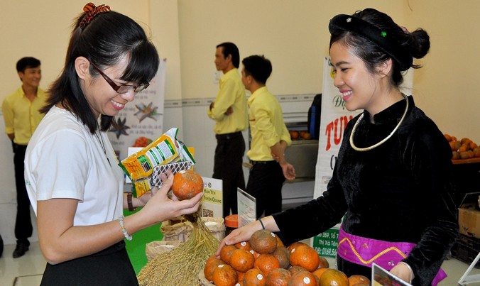 Cẩm Ly (phải) đang giới thiệu sản phẩm cam Hàm Yên (Tuyên Quang) cho khách hàng tại Hội chợ hàng Việt Nam chất lượng cao, tháng 3, tại An Giang.