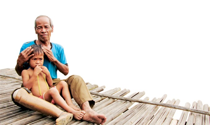 Ông Mơ đang ôm cháu Hồ Dừa (4 tuổi, mồ côi cha mẹ) vào lòng nâng niu, vỗ về. Ảnh: H.T.