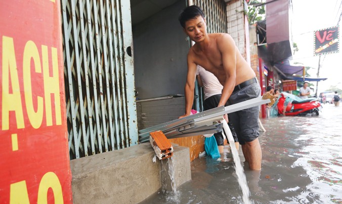 Người dân bơm nước từ nhà ra mỗi khi trời mưa trên đường Phan Huy Ích (quận 12). Ảnh: Việt Văn.