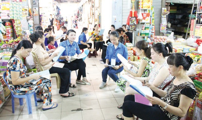 Các tình nguyện viên dạy ngoại ngữ cho các tiểu thương ngay tại chợ ở Quảng Ninh. Ảnh: T.T.