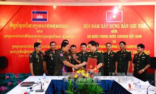 Đại tá Hàn Mạnh Thắng, Vụ trưởng Vụ Pháp chế (Bộ Quốc phòng Việt Nam, bên phải) và Đại tướng Mom Sophat, Cục trưởng Cục pháp chế (Bộ Quốc phòng Vương quốc Campuchia) ký biên bản hội đàm.