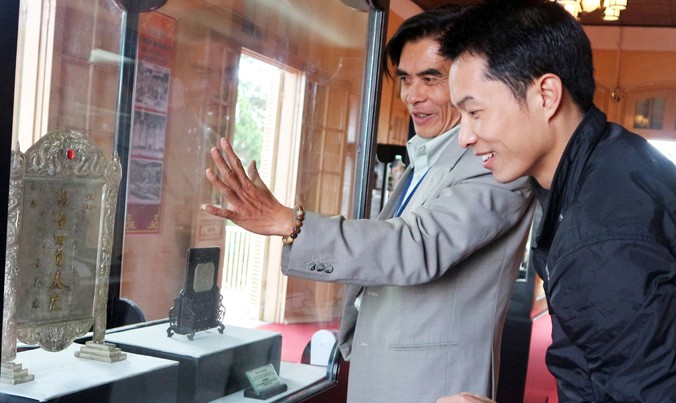 Giám đốc bảo tàng (bên trái) nói về bức trấn phong “vạn thọ tứ tuần Đại Khánh”.