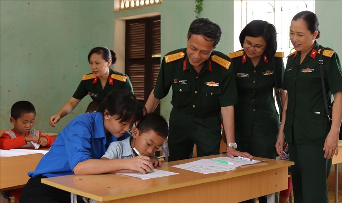 Đại tá Cao Minh Tiến và đoàn công tác kiểm tra thực tế việc bổ trợ kiến thức cho học sinh cấp 1 của đội tình nguyện tại trường Tiểu học và THCS xã Bắc Sơn. Ảnh: Nguyễn Minh.