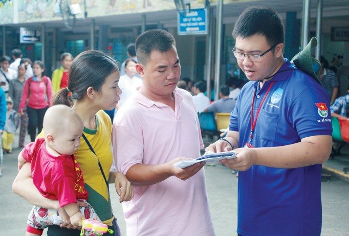 Sinh viên trường ĐH Sài Gòn hướng dẫn, tư vấn cho một đôi vợ chồng đưa con đến khám chữa bệnh tại BV Nhi đồng 1, TPHCM. Ảnh: Ngô Tùng.