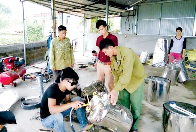 Anh Nguyễn Văn Huỳnh (đứng, áo ngắn tay) trao đổi với công nhân đang sản xuất bếp nóng lạnh.