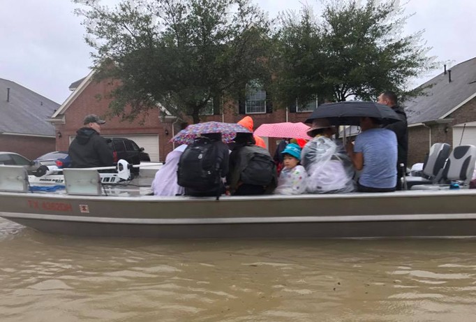 Một số người Việt dùng xuồng cá nhân để vận chuyển người từ vùng ngập tới nơi tạm lánh. Ảnh: Danny Nguyễn.