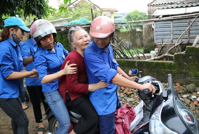 Thanh niên tình nguyện hỗ trợ người già tại huyện Nghi Xuân đến nơi trú bão.
