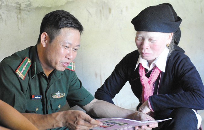 Thiếu tá Phạm Công Khanh hỏi thăm việc học, luyện chữ của chị Phàn Thị Hằng. Ảnh: Xuân Tùng.