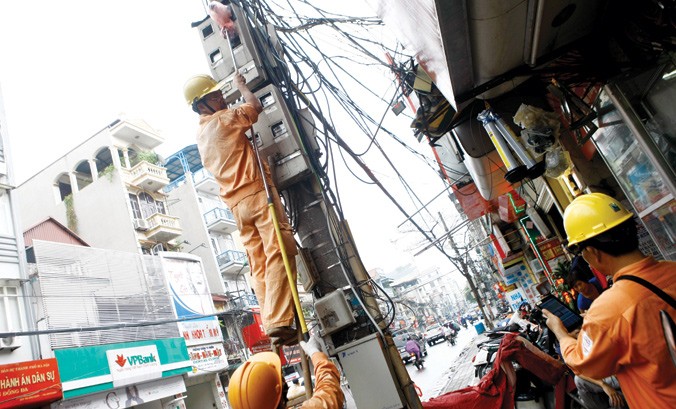 Công nhân điện lực Hà Nội đang đo số công tơ điện của từng hộ dân trên phố Khâm Thiên - Hà Nội. Ảnh: Như Ý.