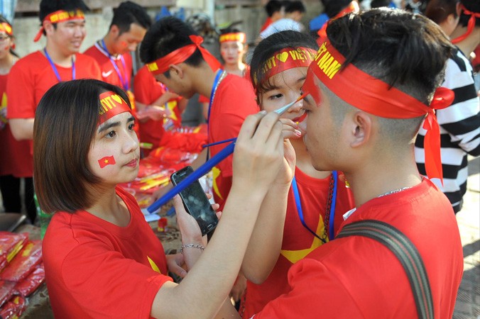 Không khí sục sôi hướng đến trận chung kết lịch sử của bóng đá Việt Nam được các bạn trẻ chia sẻ trên mạng xã hội. Trong ảnh, cổ động viên Hà Nội giúp nhau vẽ cờ đỏ sao vàng lên má để cổ vũ. Ảnh: Xuân Tùng.