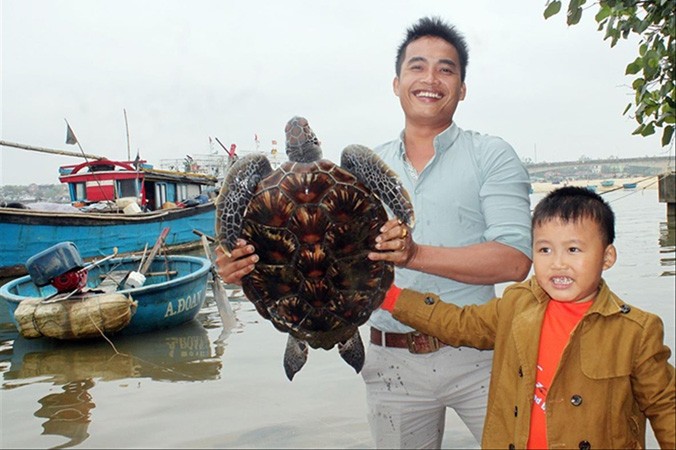 Cha con anh Nguyễn Văn Đoàn giao lại con rùa quý hiếm cho cơ quan chức năng để thả về lại biển.