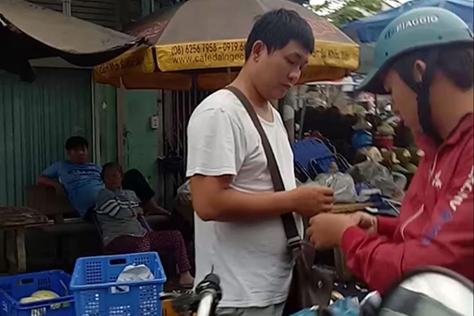 Một “người lạ” đứng thu tiền xe vào chợ.