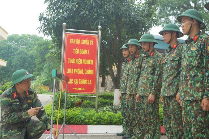 Thiếu tá Nguyễn Văn Thanh (trái) hướng dẫn đồng đội sử dụng thước bắc cầu TMM-3M đa năng dùng pin sạc do anh sáng chế, nhằm rút ngắn thời gian thao tác bắc dỡ cầu, nhất là vào ban đêm. Ảnh: NGUYỄN MINH.