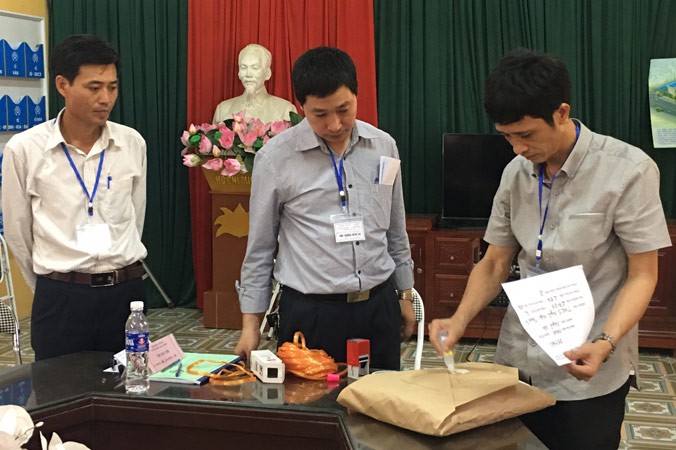 Cán bộ làm thi tại điểm thi THCS Ngũ Hiệp (Thanh Trì) đang dán, niêm phong bài thi trước sự chứng kiến của thư ký, thanh tra. Ảnh: Nguyễn Hà.