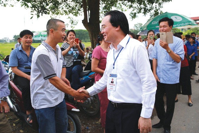 Bộ trưởng Phùng Xuân Nhạ trò chuyện với phụ huynh bên lề kỳ thi THPT Quốc gia 2018 tại Hoài Ðức, Hà Nội. Ảnh: Như Ý.