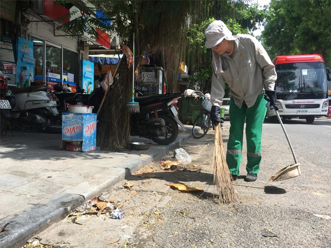 Công nhân Cty Urenco Hà Nội đi dọn vệ sinh vỉa hè trên phố Phủ Doãn. Ảnh: Trường Phong.
