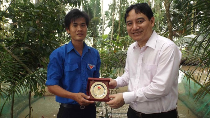 Anh Nguyễn Đắc Vinh tặng biểu trưng cho anh Khoa tại khu nuôi ếch. Ảnh: Hòa Hội