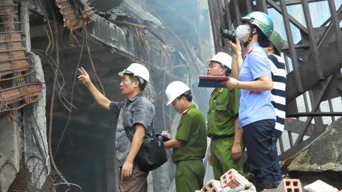 Thượng tá Nguyễn Viết Nội (đầu tiên, đang chỉ tay) cùng đại diện các cơ quan chức năng khám nghiệm hiện trường vụ cháy ở Trung tâm Thương mại Hải Dương