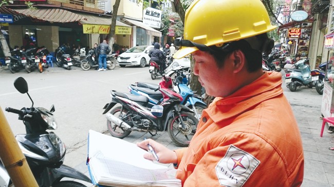 Công nhân Công ty điện lực Hoàn Kiếm đang chốt chỉ số công tơ từng hộ dân trên phố Đường Thành, Hà Nội. Ảnh: Như ý