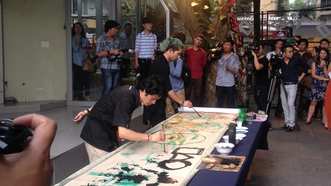 Hai nghệ sỹ Xuân Như và Yoyo đang thực hiện bức tranh giấy dó khổ lớn. Ảnh: Anh Thư
