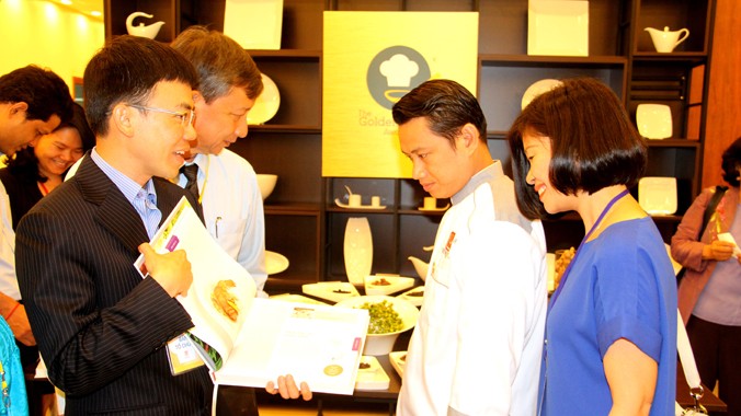 Ông Lý Huy Sáng - Phó trưởng Ban tổ chức (bìa trái) giới thiệu sách “Chiếc thìa vàng” vừa xuất bản. Sách tập hợp các món ăn đạt giải cao trong cuộc thi “Chiếc thìa vàng” mùa đầu tiên